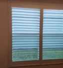 White window shutters with green view.