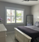 White bedroom with bed, window, and dresser.