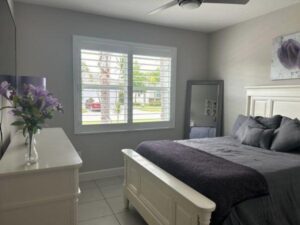 A bedroom with a bed, dresser and window.